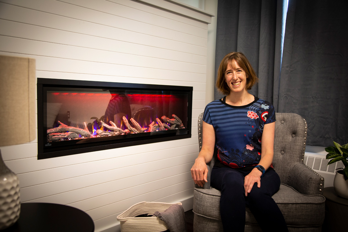 Applied Health Sciences Professor Shannon Mejía sits by fireplace.