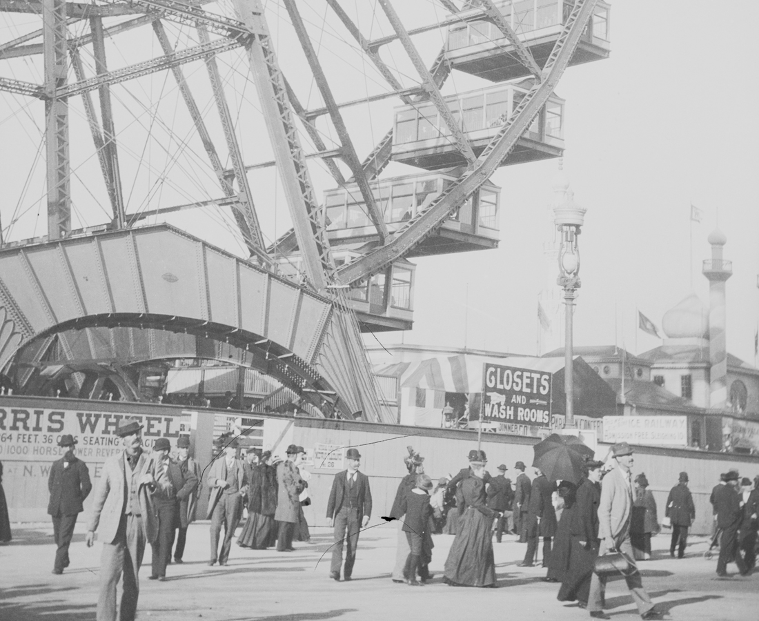 black and white photo of a ferris wheel with patrons walking on the ground in front